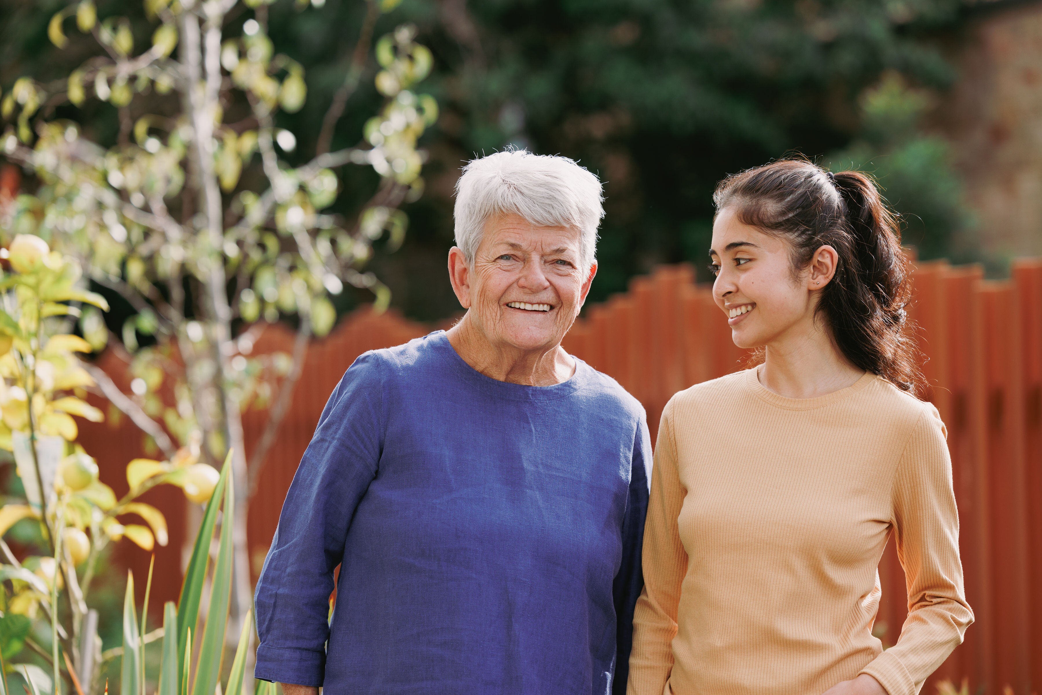 A woman and a carer sitting on a bed at HammondCare Caulfield residential aged care in Melbourne